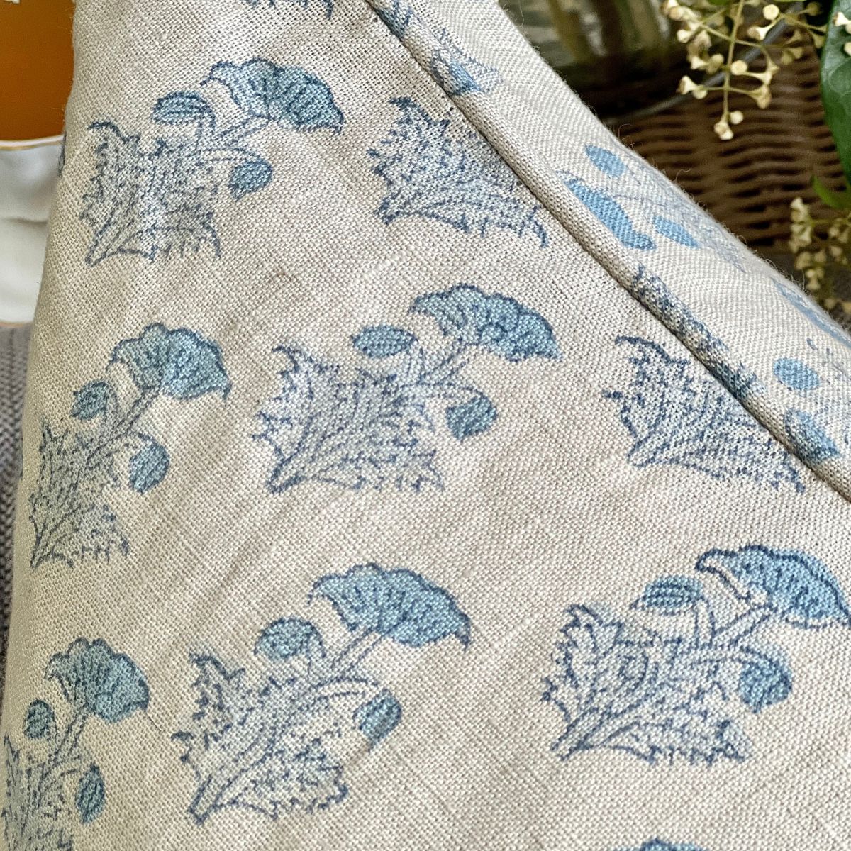 
A close-up of the Tranquil Blue monochrome floral hand block printed pure linen cushion cover on a sofa, showing the intricate floral motif and natural linen texture.