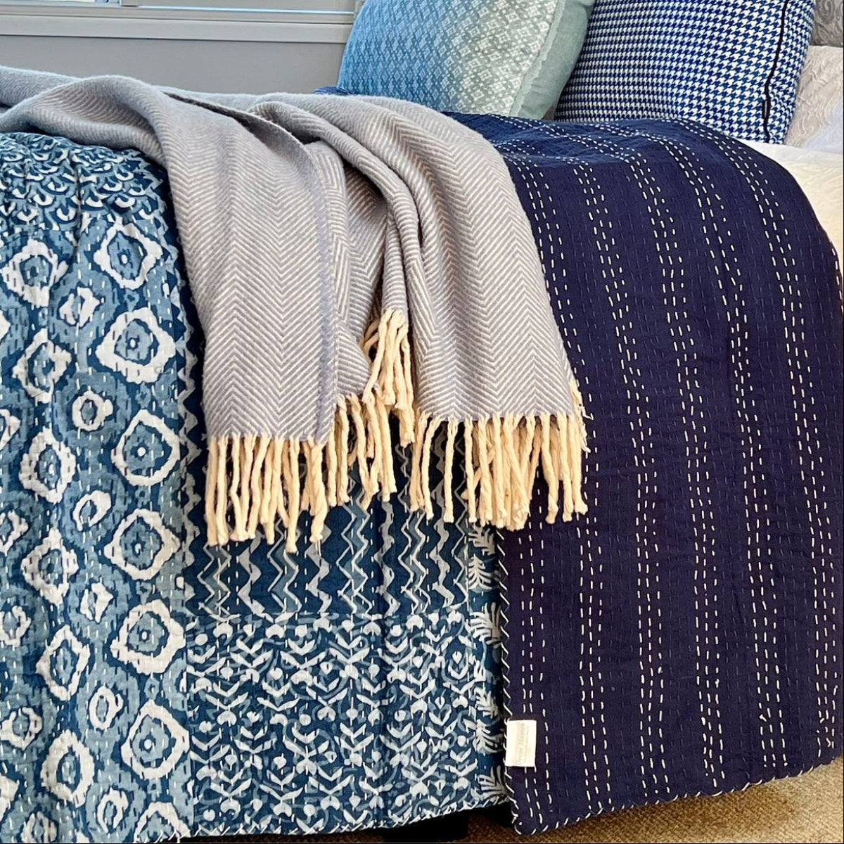 Close-up of a blue and white patchwork Kantha quilt highlighting intricate hand stitching, mixed block print fabrics, and exceptional handmade quality.