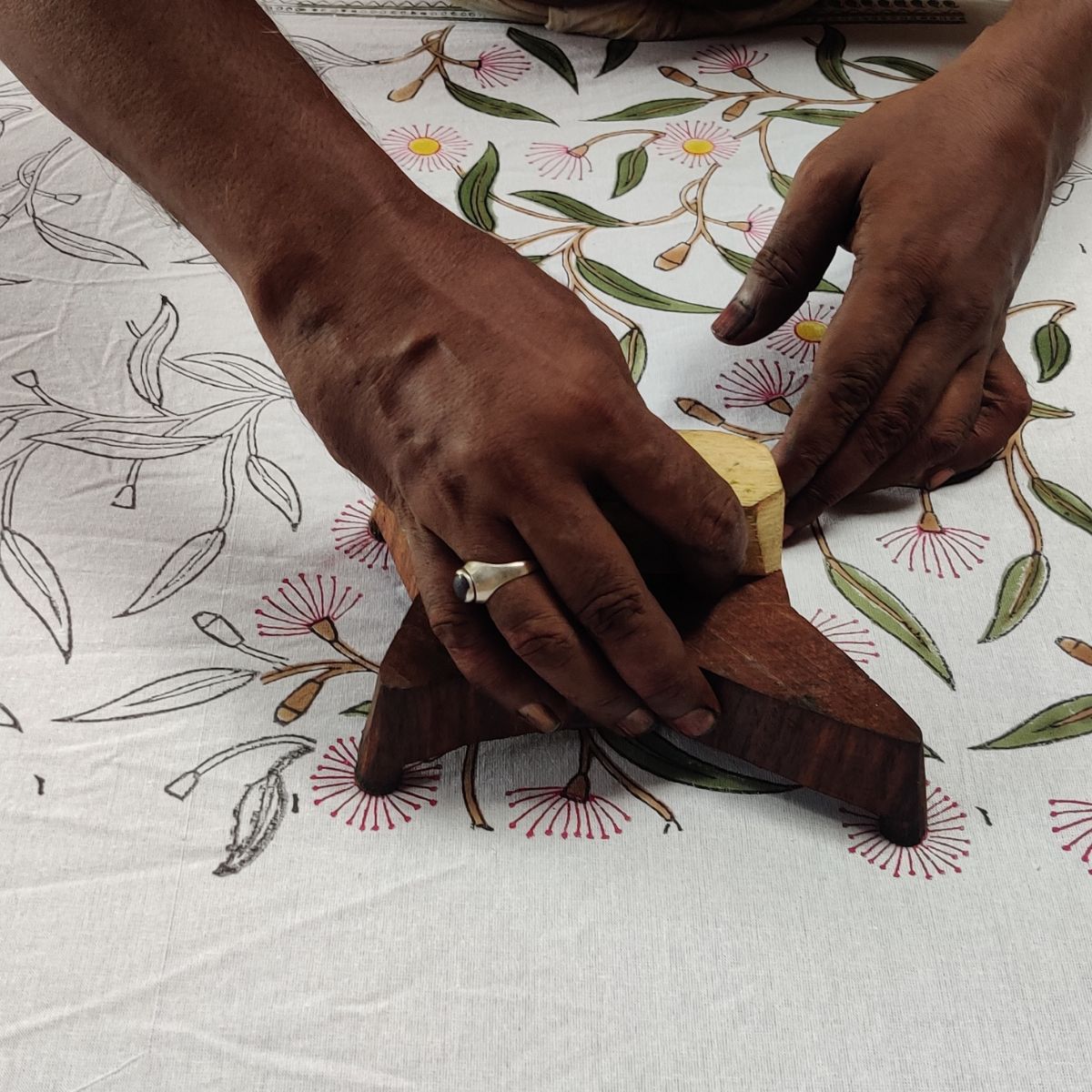 Indian artisan hand printing the Pink Green Flowering Gums tablecloth using traditional wooden blocks, creating unique handcrafted square table linens.