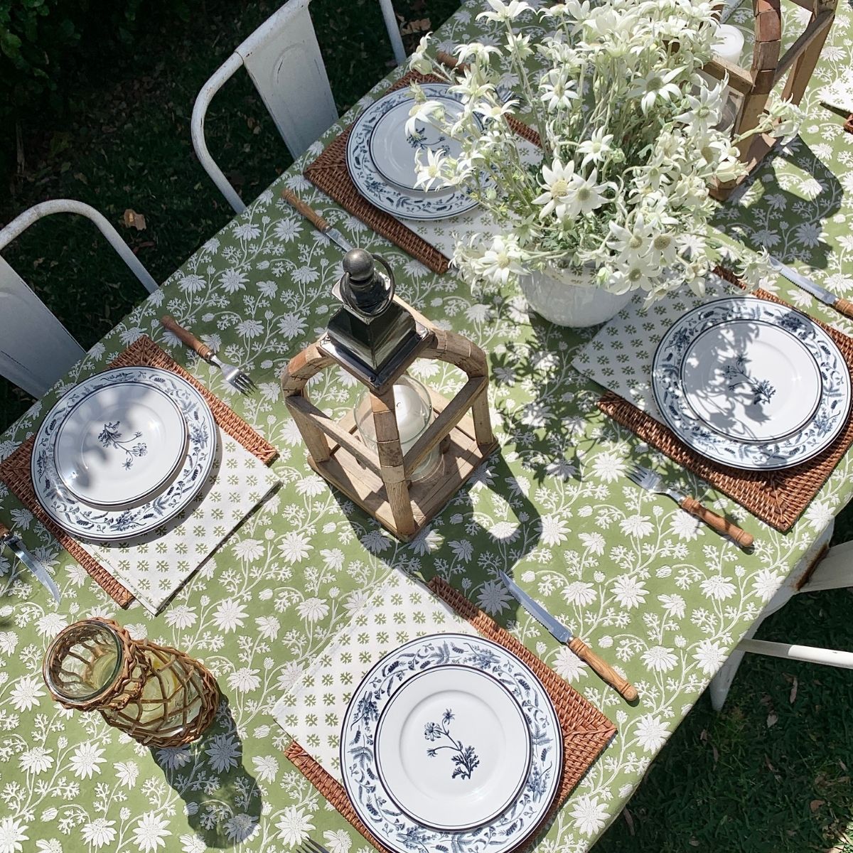 Flannel Flowers hand block printed tablecloth styled for outdoor spring and summer dining with fresh flowers and layered tableware.