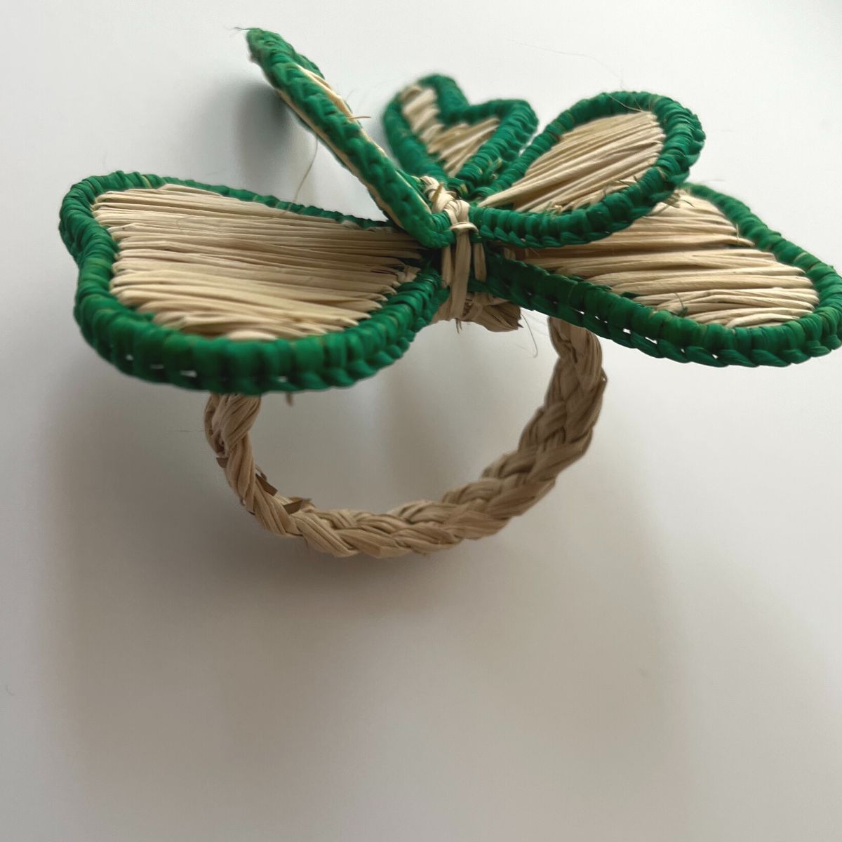 
Detailed view of green bow napkin rings handmade by indigenous artisans in Colombia using natural raffia, perfect for Christmas entertaining and seasonal table settings.