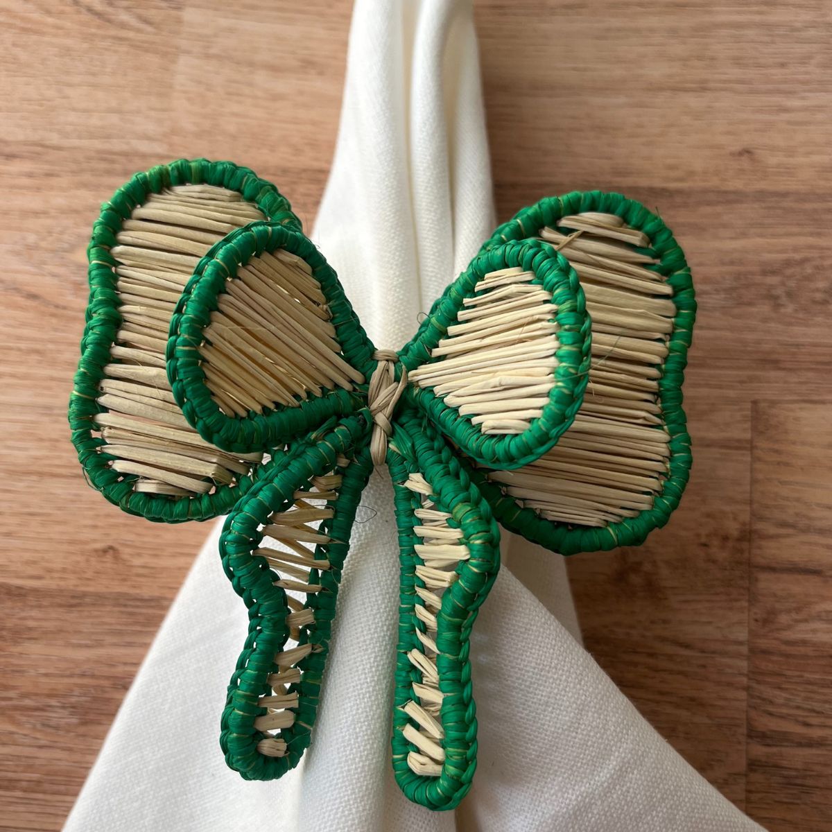 Artisan-made green bow napkin ring paired with a cloth napkin, showcasing natural Iraca straw craftsmanship for elegant Christmas and everyday dining.