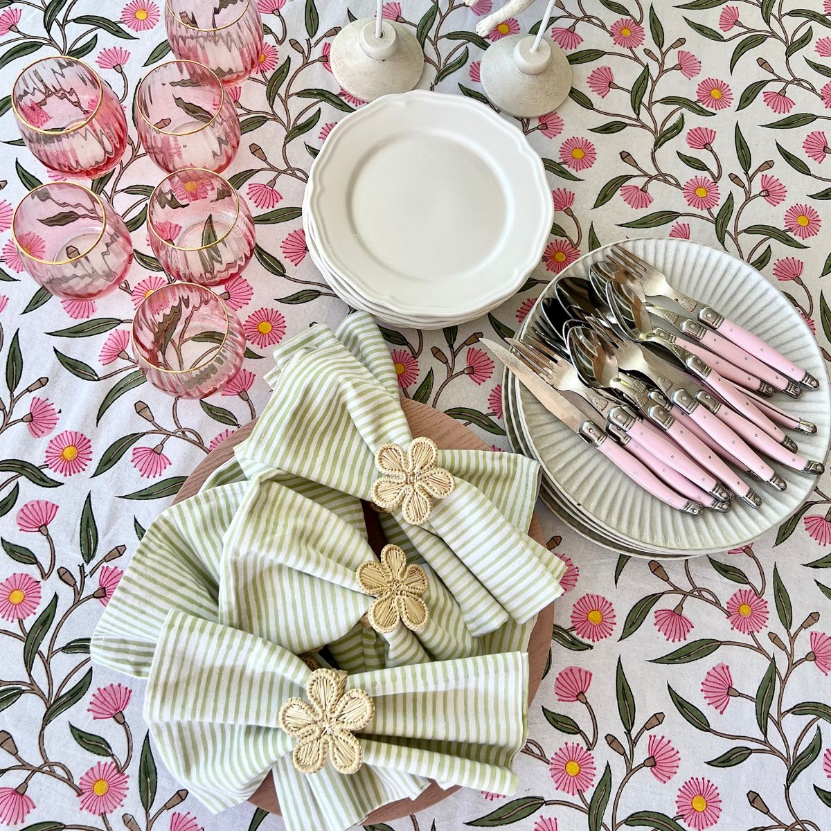 Rectangular table setting featuring green striped cotton napkins folded over charger and styled with floral napkin rings for elegant entertaining and special occasions.
