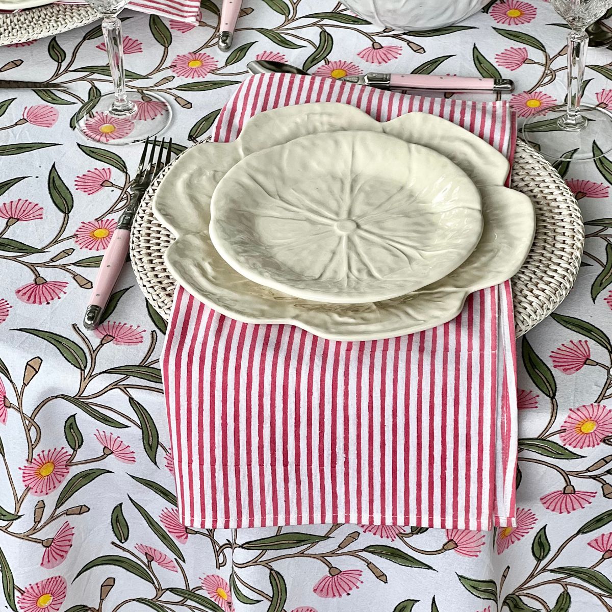 Pink striped cotton napkins and white dinnerware styled on the Pink Green Flowering Gums round tablecloth, available in 150 cm, 180 cm, and 220 cm sizes for everyday dining and entertaining.