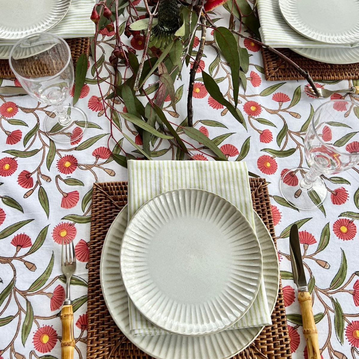 180 x 340 cm Red Flowering Gums tablecloth styled for outdoor entertaining with seasonal decorations and place settings.