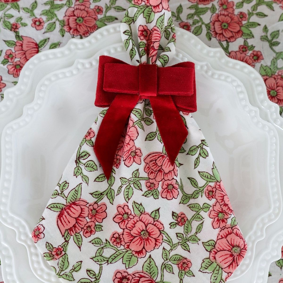 Christmas table napkin set of 4, featuring red pink green floral pattern on white cotton base.