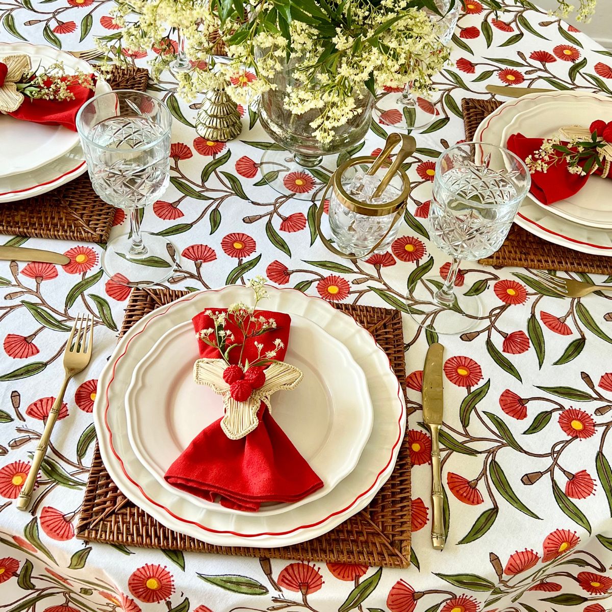 Top view of 180 cm Red Flowering Gums round tablecloth styled with festive Christmas décor, candles, and holiday tableware.